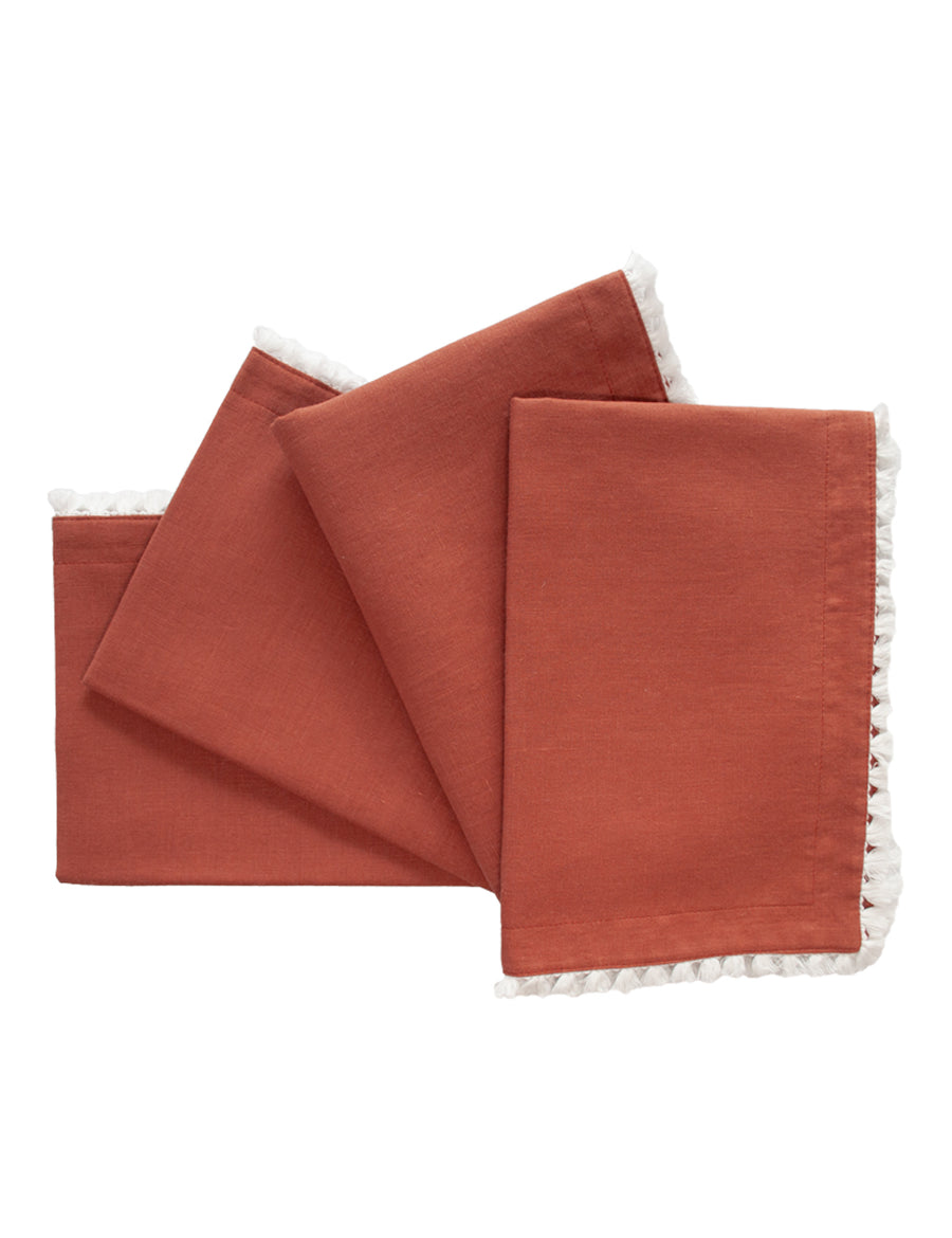 a set of linen placemat in rust colour with cotton tassel trim