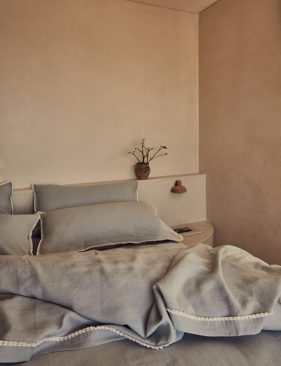 lifestyle shot of the linen quilt set in cloud colour and finished in our contrast organic cotton tassel trim with rustic decor