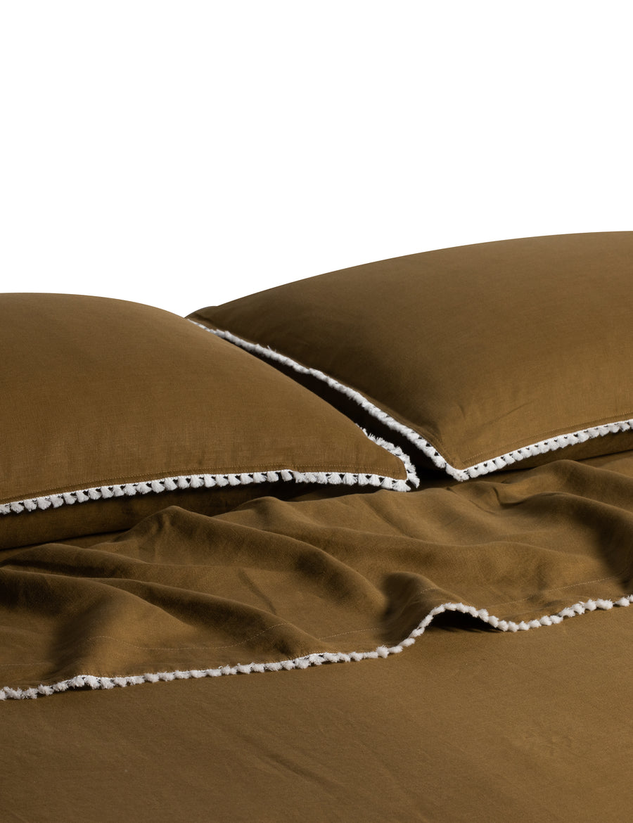 linen sheet set in olive colour and finished in our contrast organic cotton tassel trim