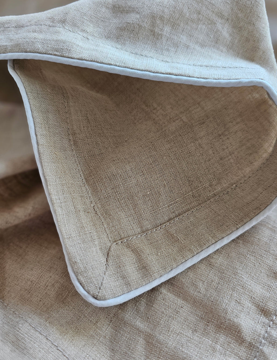 detail shot of the linen table napkins in natural colour with white piping
