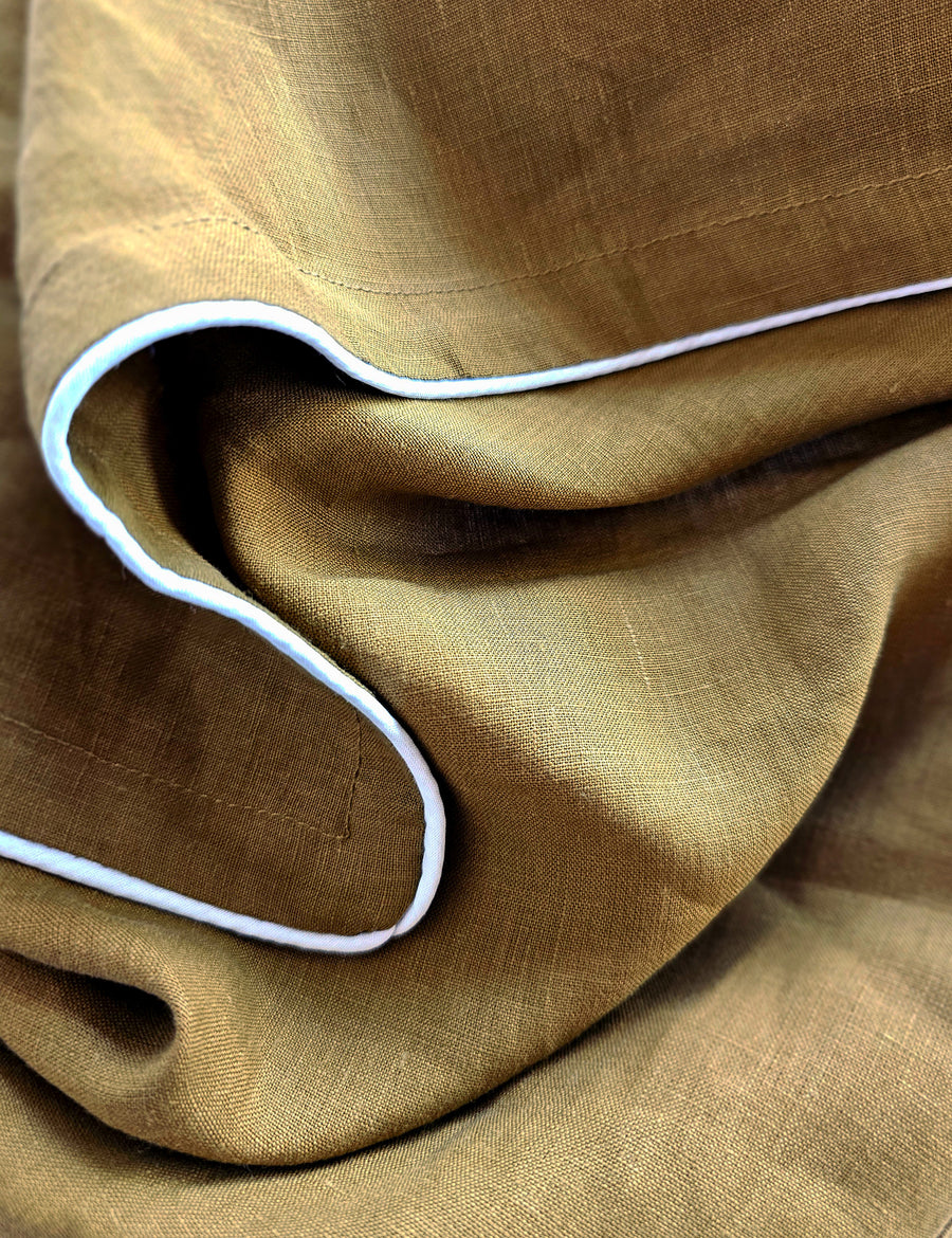 detail shot of the linen table napkins in olive colour with white piping