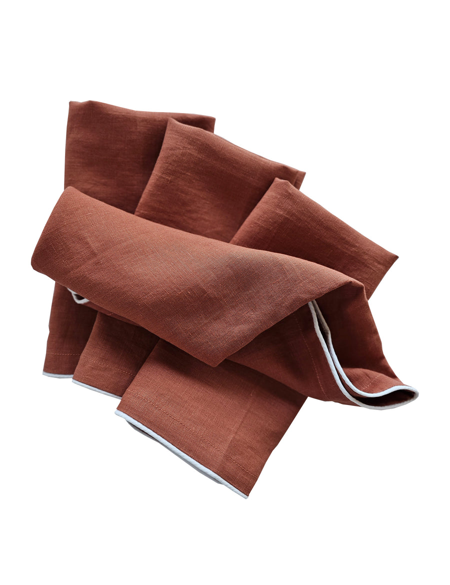 linen table napkins in rust colour with white piping
