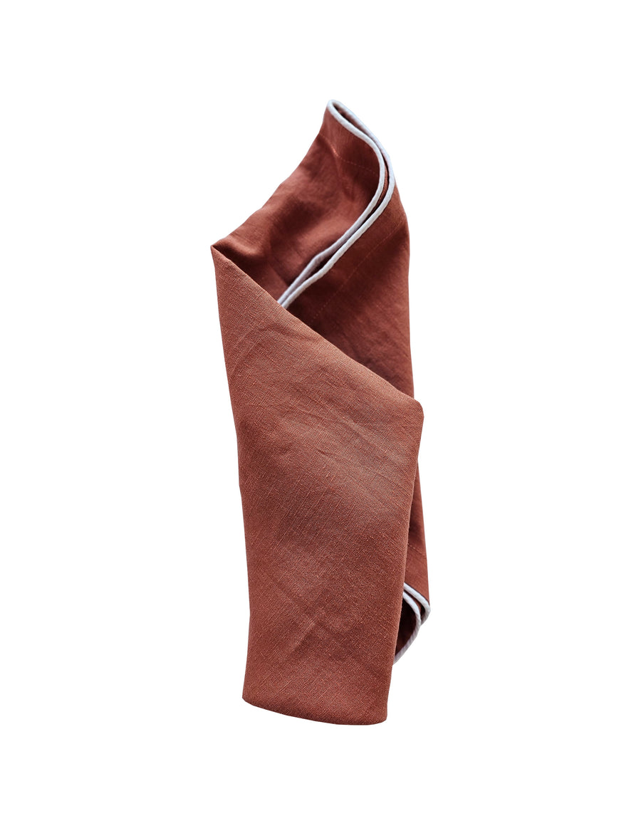 linen table napkin in rust colour with white piping