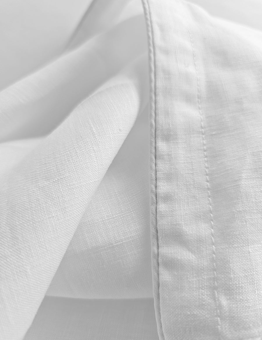 detail shot of the linen table napkins in white colour with white piping