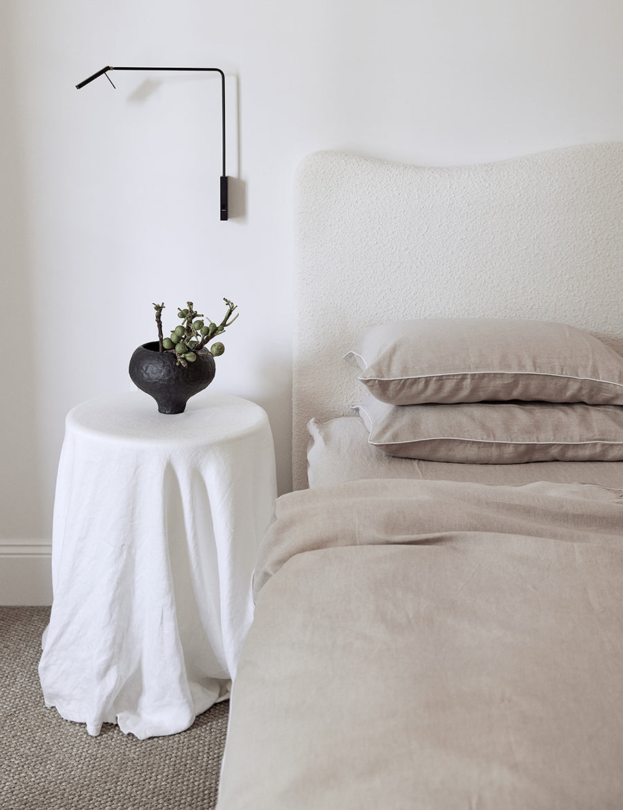 minimalistic photography of the linen piped sheet set in natural with white piping details