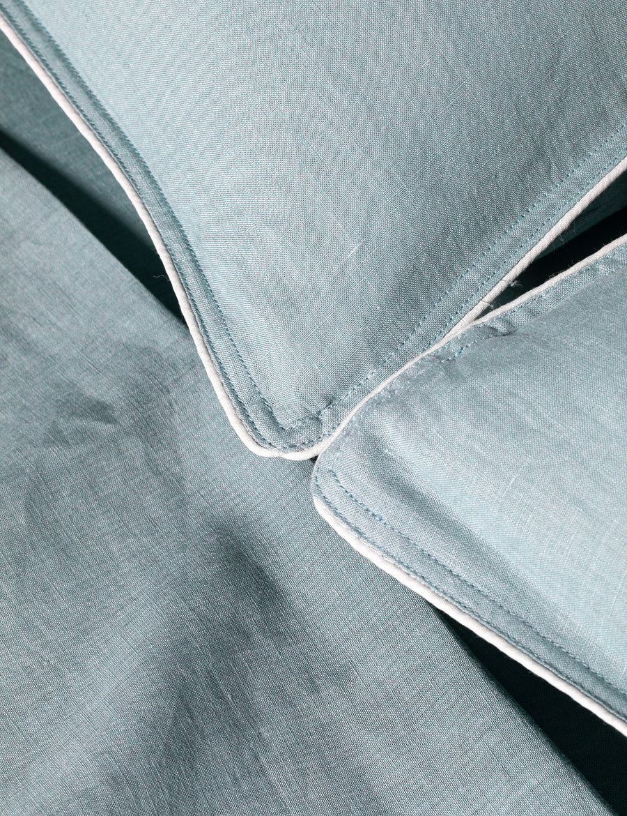 details of piped pillowcases in azure colour with contrast piping in white