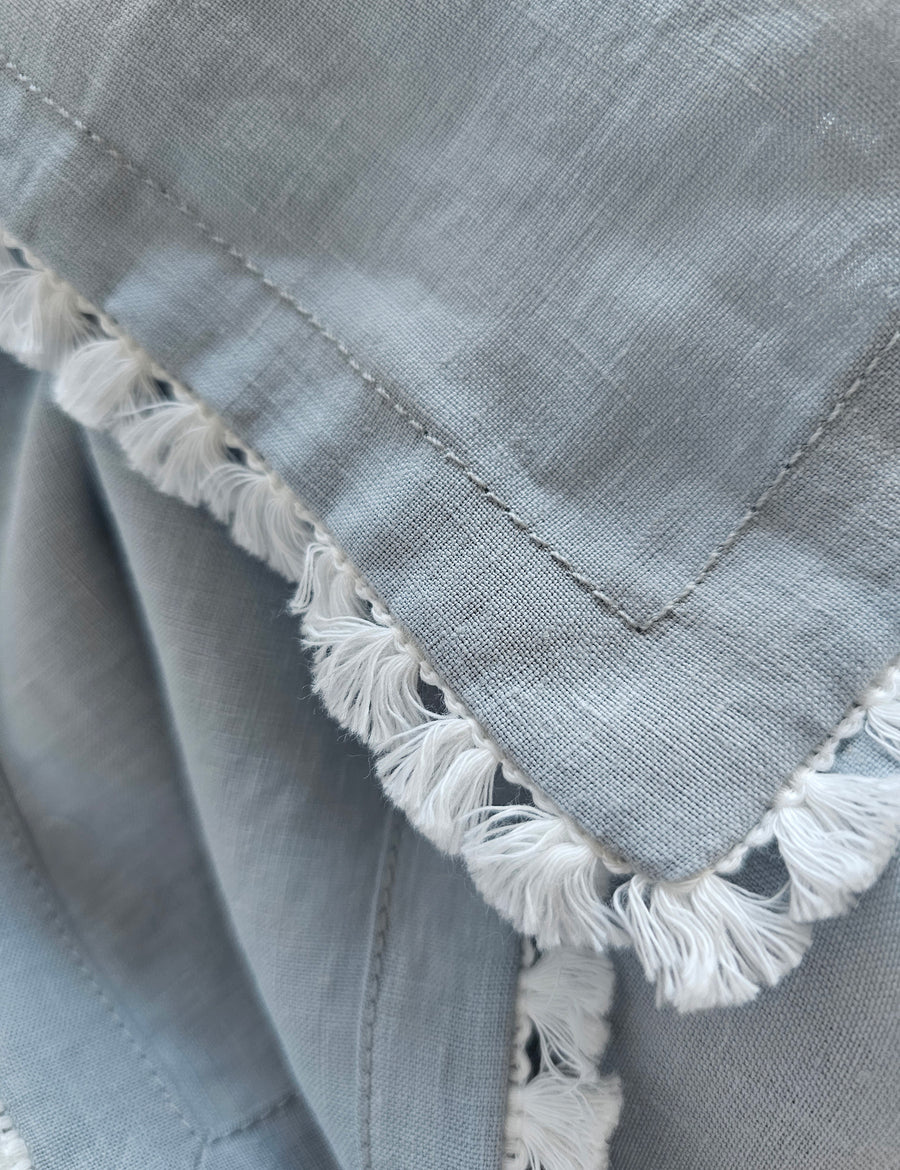 details shot of the linen table napkin in cloud colour with cotton tassel trim in white