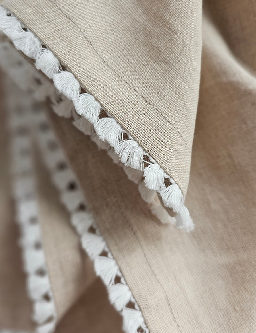 details shot of the linen table napkin in natural colour with cotton tassel trim in white