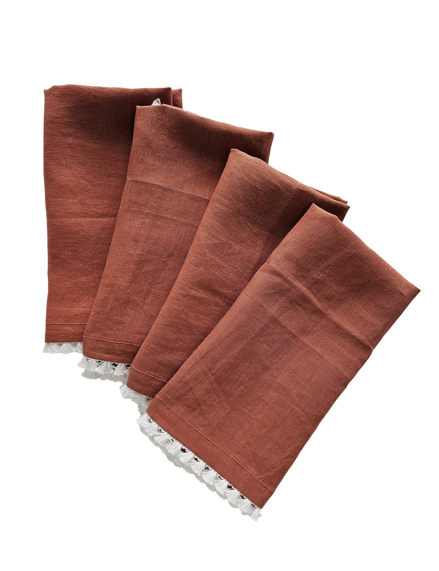linen table napkins in rust colour with cotton tassel trim in white