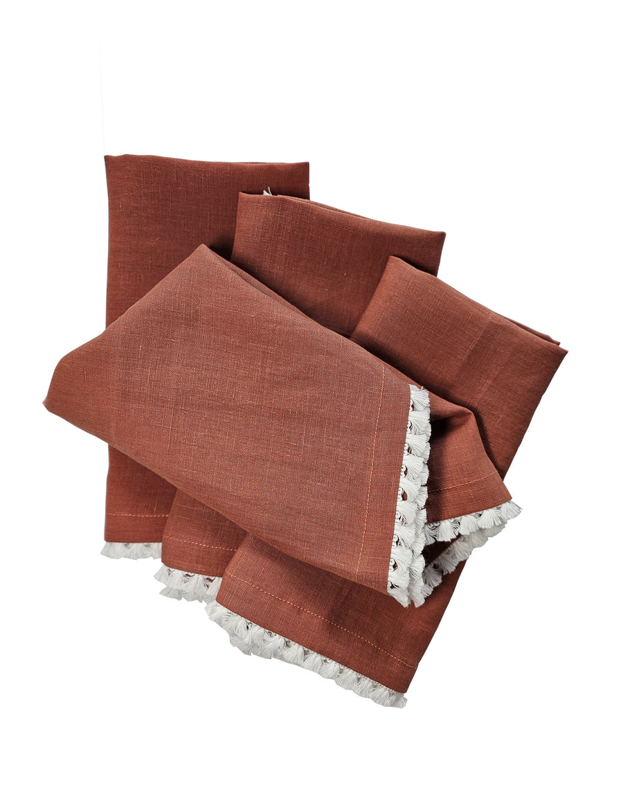 linen table napkins in rust colour with cotton tassel trim in white