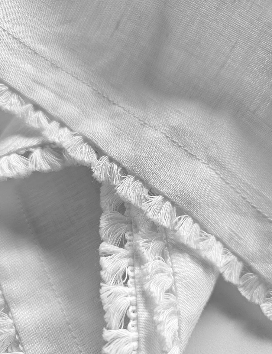 details shot of the linen table napkin in white colour with cotton tassel trim in white