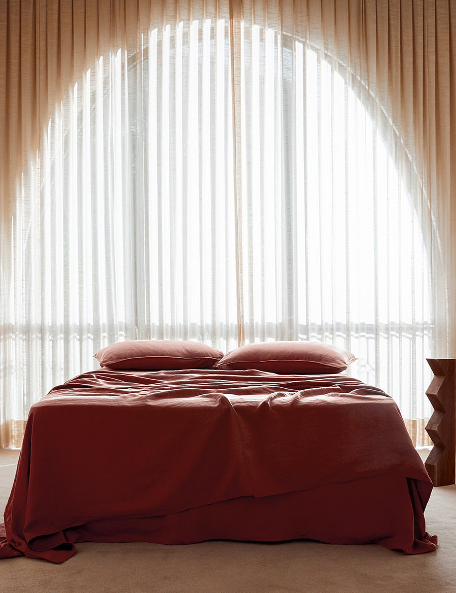 lifestyle shot of the classic linen sheet set in maple with modern decor and arched window
