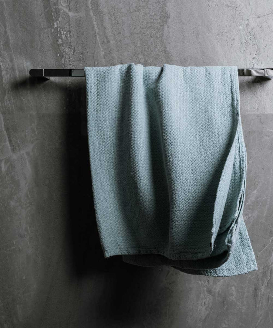 hanging photo of pure linen jacquard bath towel in azure colour with dark grey marble wall