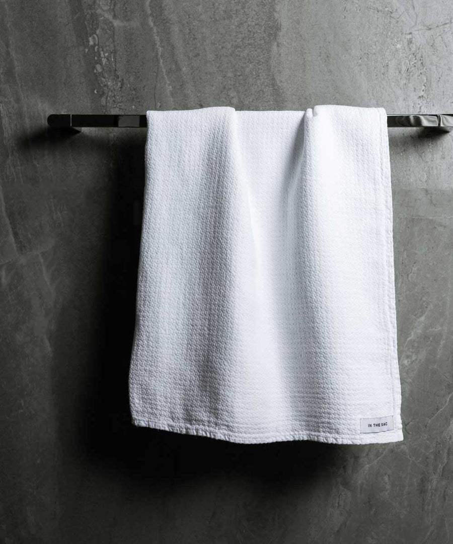 hanging linen jacquard bath towel in white colour with dark grey marble wall