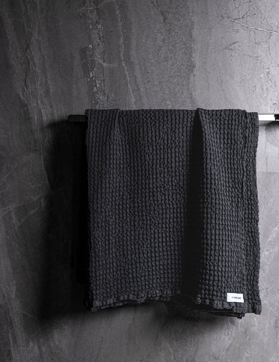 hanging linen waffle bath towel in charcoal colour with dark grey marble wall