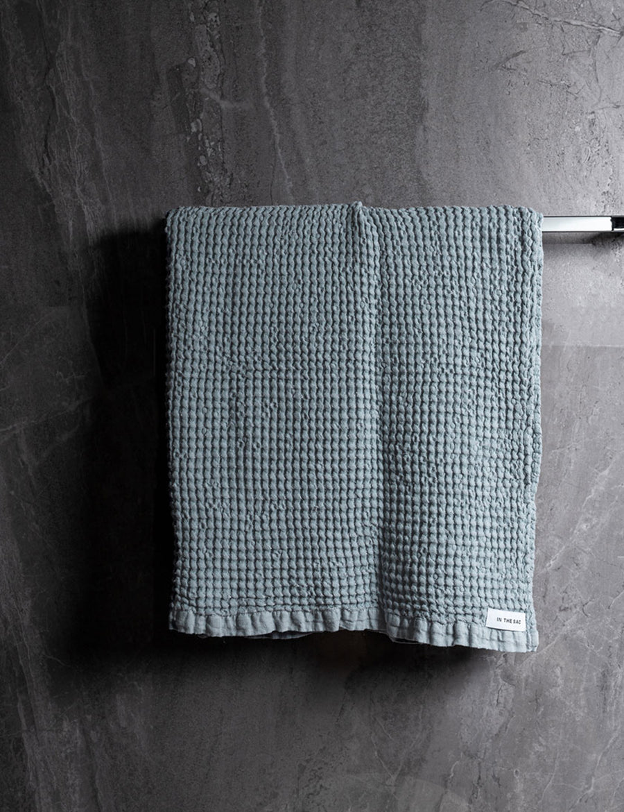 hanging linen waffle bath towel in cloud colour with dark grey marble wall