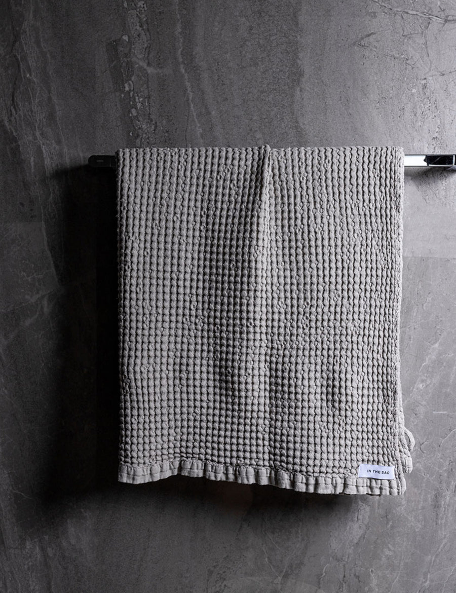 hanging linen waffle bath towel in grey colour with dark grey marble wall