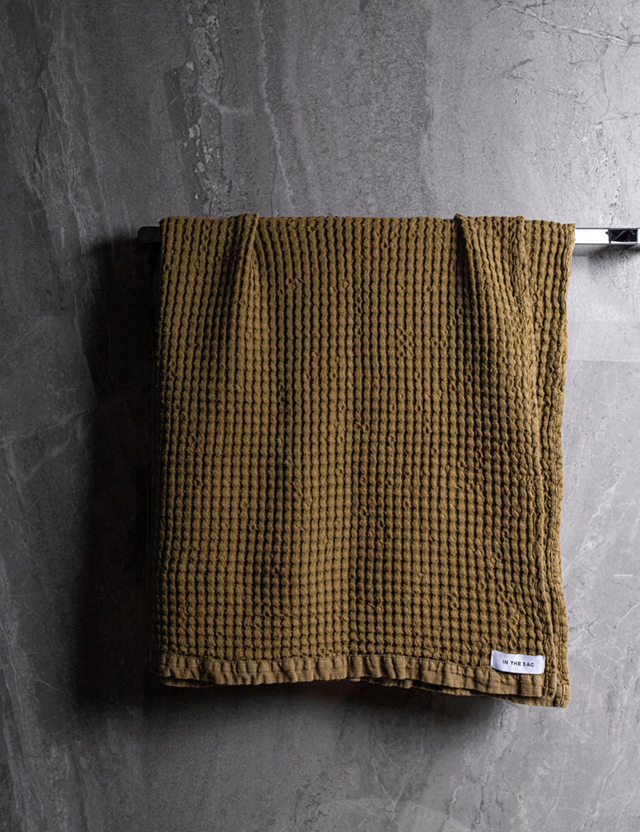 hanging linen waffle bath towel in olive colour with dark grey marble wall
