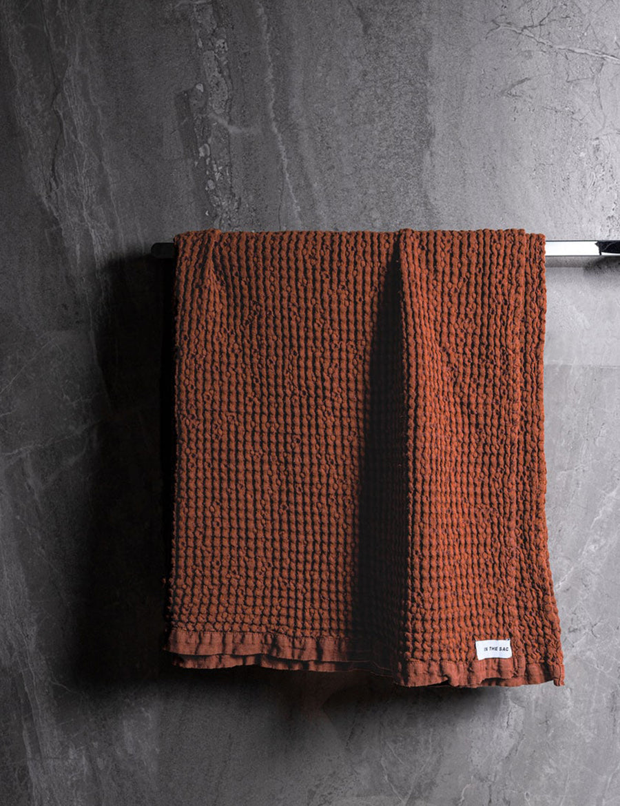 hanging linen waffle bath towel in rust colour with dark grey marble wall