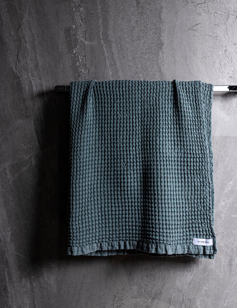 hanging linen waffle bath towel in amazon colour with dark grey marble wall