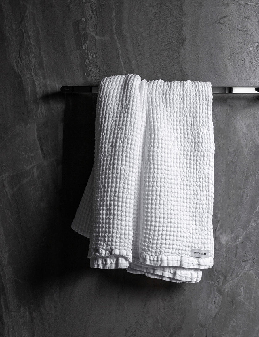 hanging linen waffle bath towel in white colour with dark grey marble wall