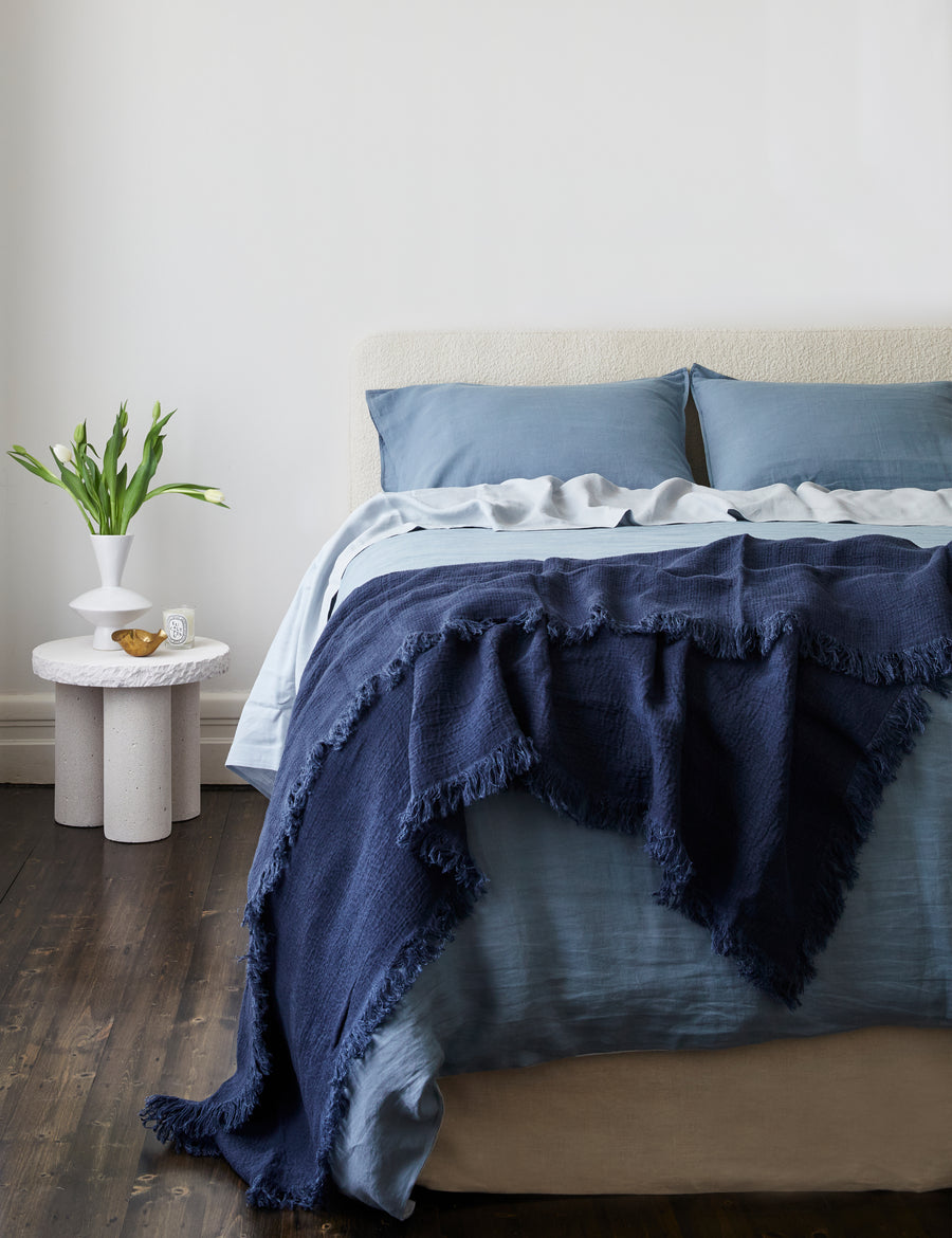 lifestyle shot of the textured linen throw in denim colour paired with blue bedding and modern decor