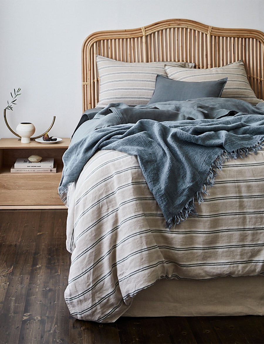 lifestyle shot of the textured linen throw in amazon colour paired with stripes bedding and modern decor
