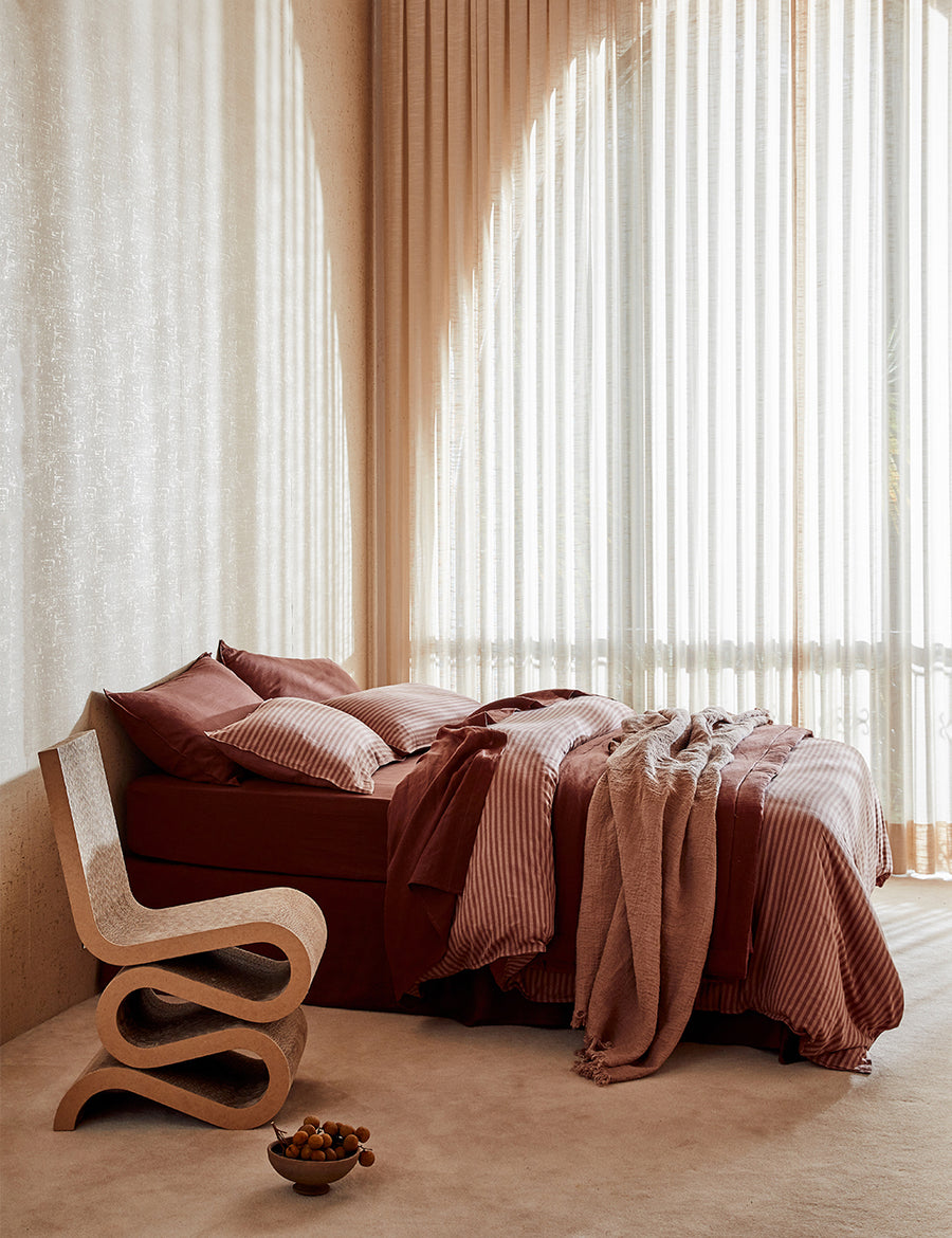 lifestyle shot of the reversible linen quilted coverlet maple and grenache with rustic decor and arched window