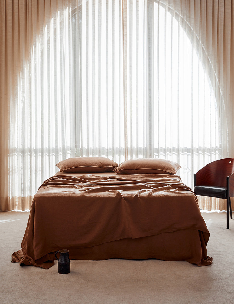 lifestyle shot of the classic linen sheet set in cognac with vintage decor and arched window