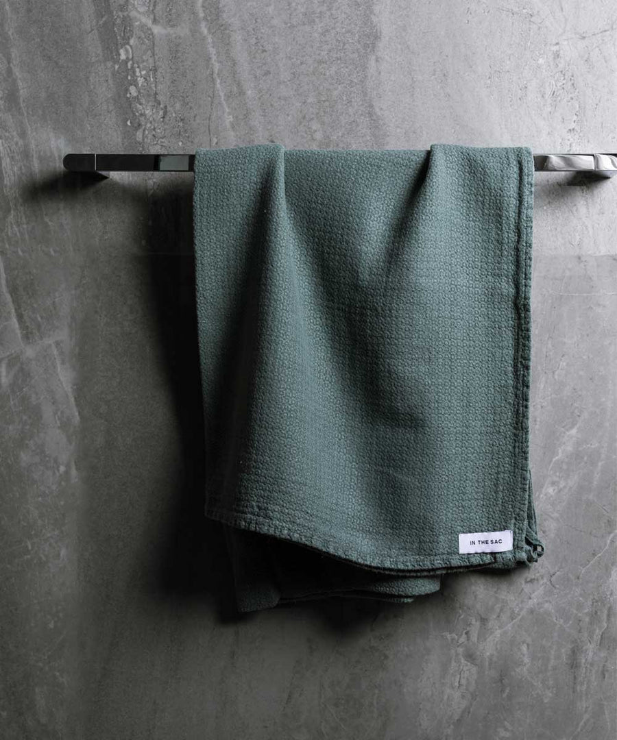 hanging photo of pure linen jacquard bath towel in amazon colour with dark grey marble wall