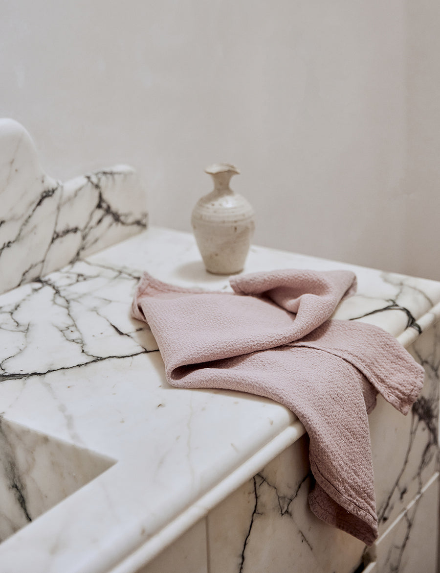 lifestyle shot of pure linen jacquard hand towel in musk colour with marble sink and decorative plants