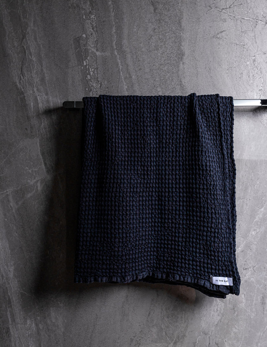 hanging photo of linen waffle bath towel in navy colour with dark grey marble wall