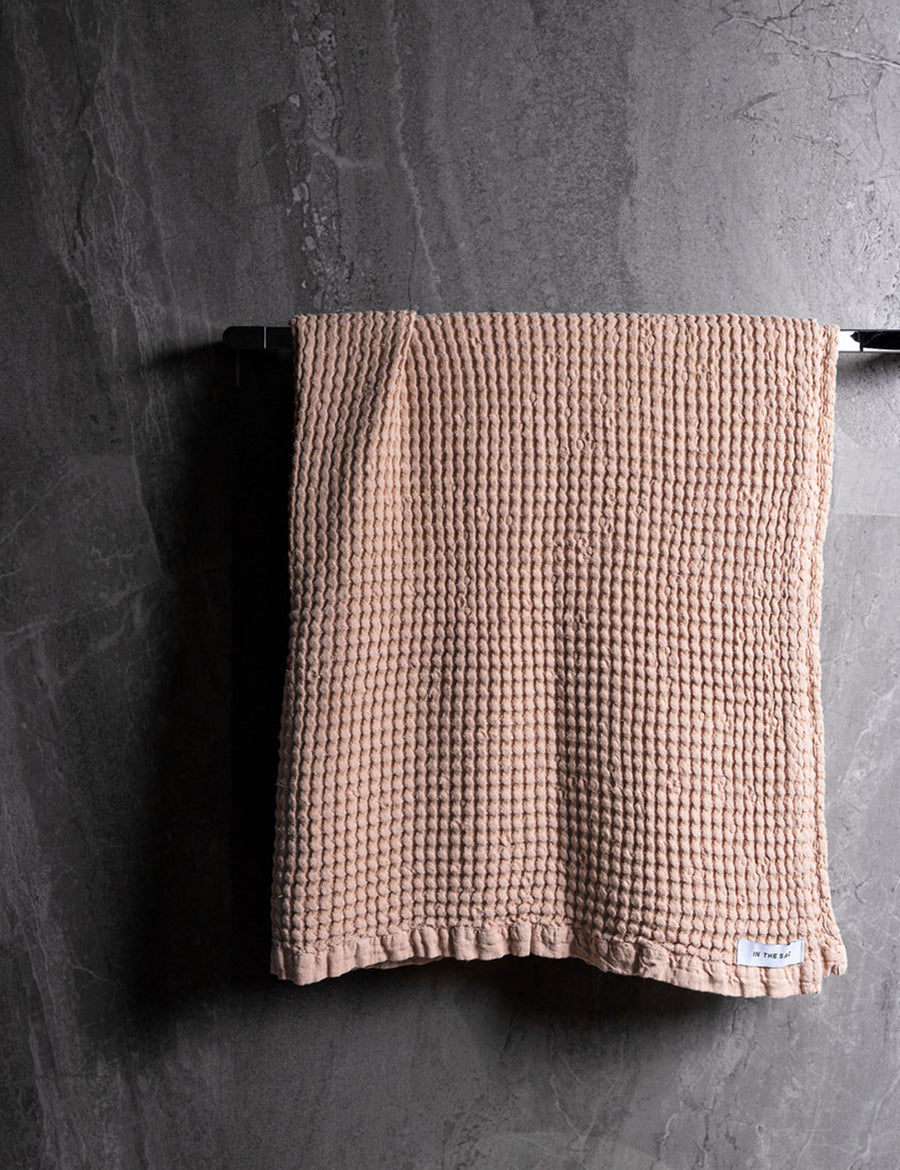 hanging photo of linen waffle bath towel in nude colour with dark grey marble wall