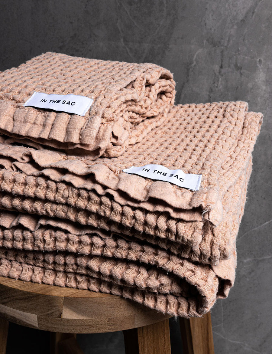 stacked photo of linen waffle hand towel in nude colour with matching bath towel on wooden stool