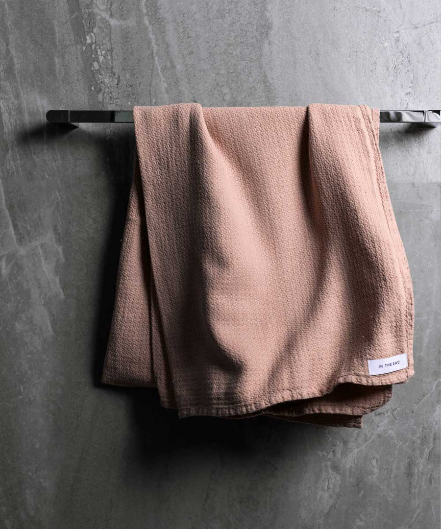 hanging linen jacquard bath towel in nude colour with dark grey marble wall