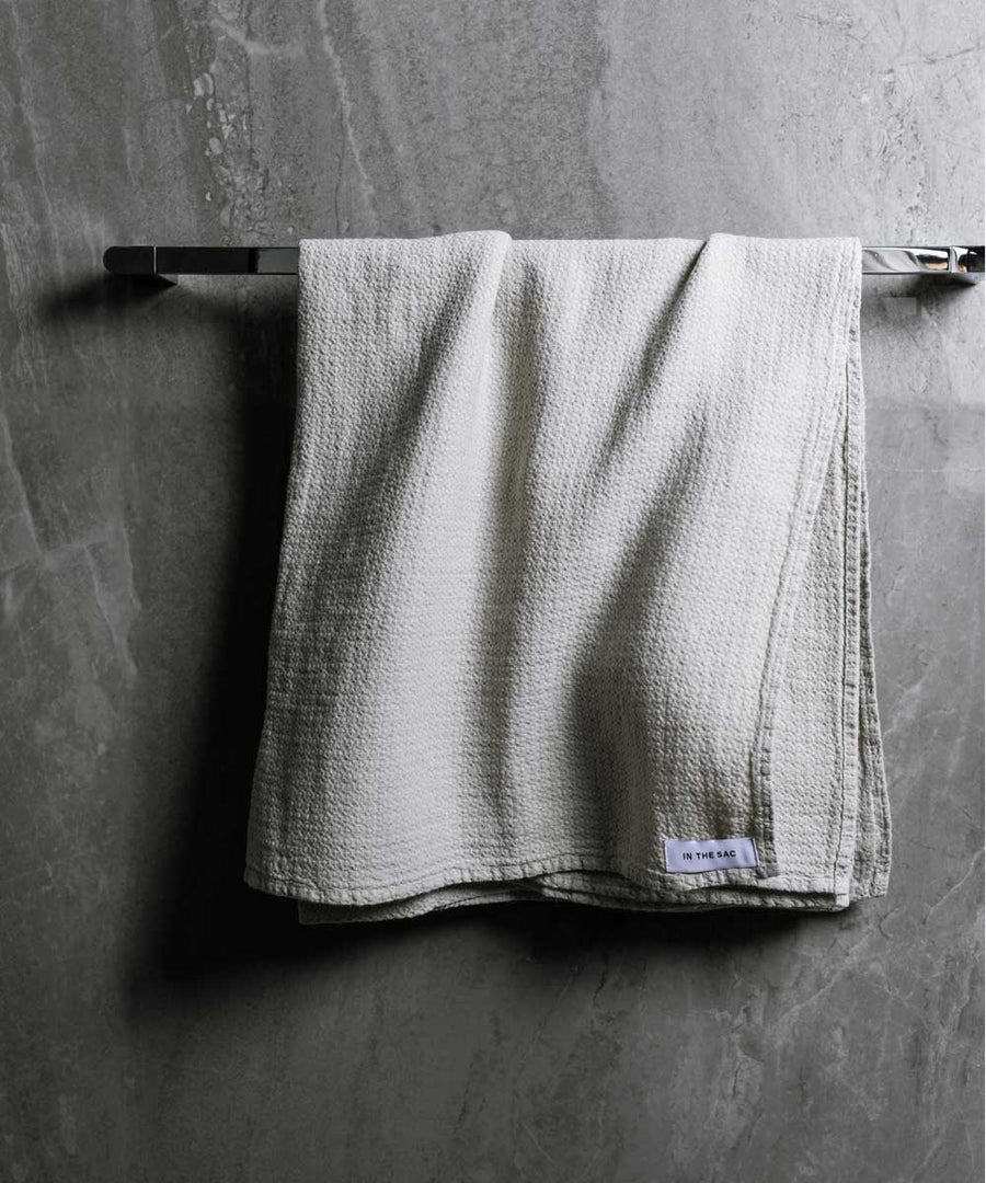 hanging linen jacquard bath towel in grey colour with dark grey marble wall
