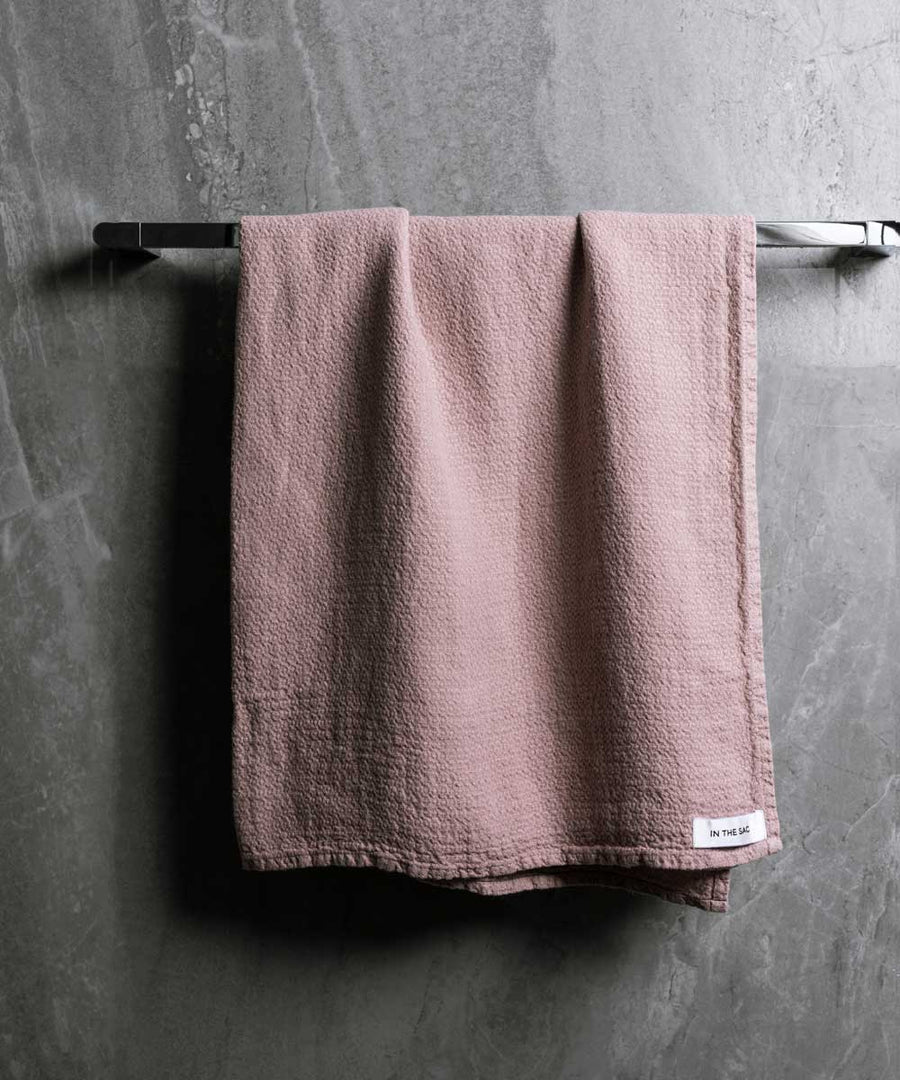 hanging linen jacquard bath towel in musk colour with dark grey marble wall