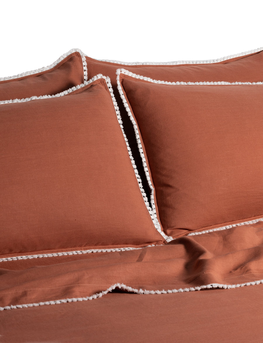 linen quilt set in rust colour and finished in our contrast organic cotton tassel trim