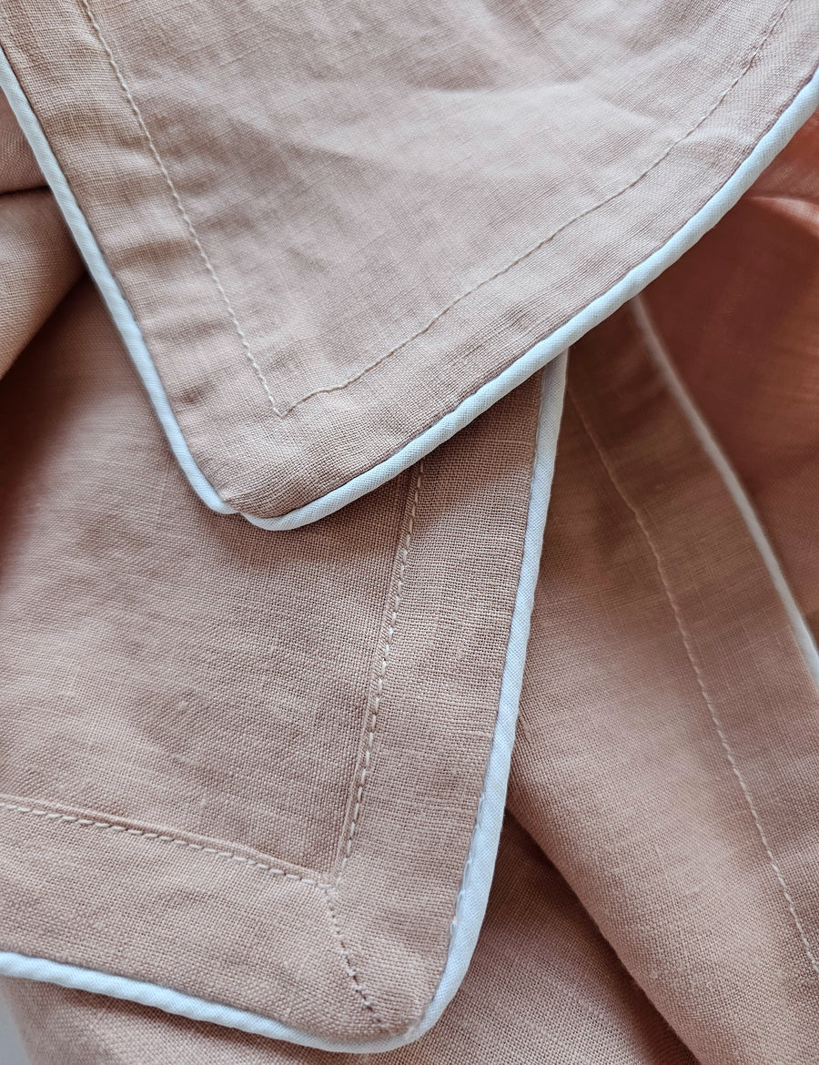 detail shot of the linen table napkins in blush colour with white piping