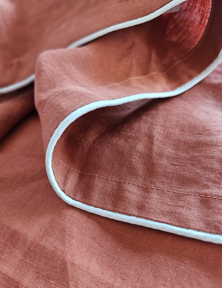 detail shot of the linen table napkins in rust colour with white piping