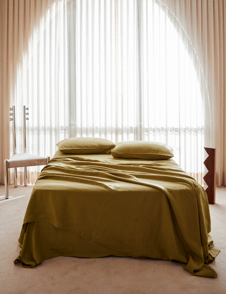lifestyle shot of the classic linen sheet set in willow with vintage decor and arched window
