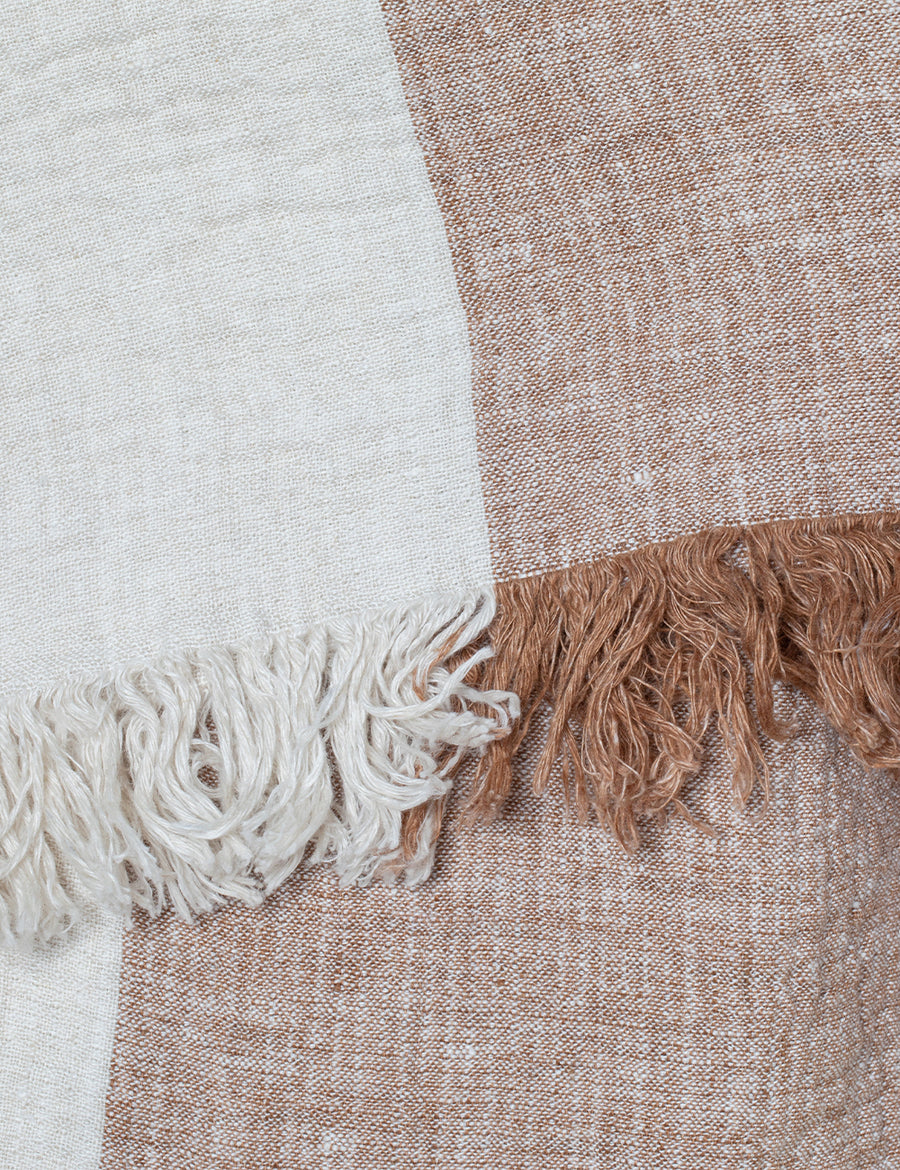 detail shot of textured linen throw with fringe trim in colour block caramel with natural