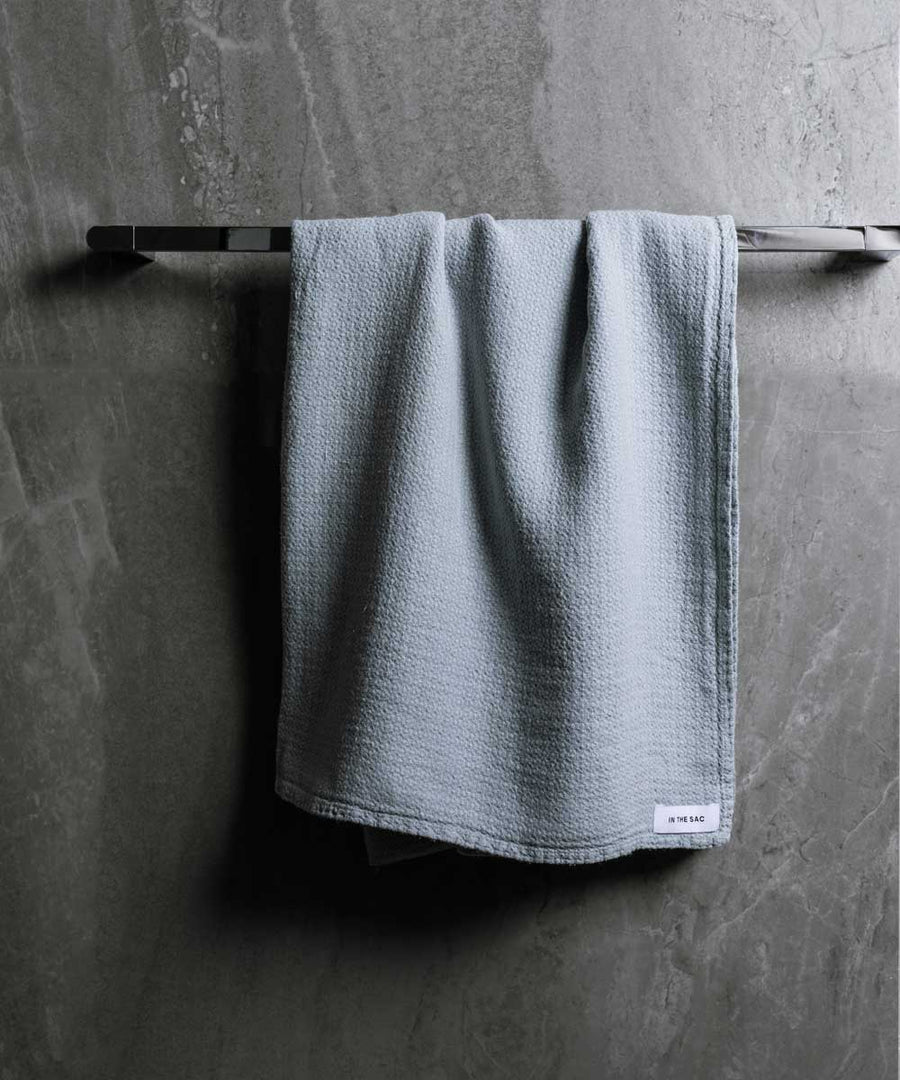 hanging photo of pure linen jacquard bath towel in cloud colour with dark grey marble wall