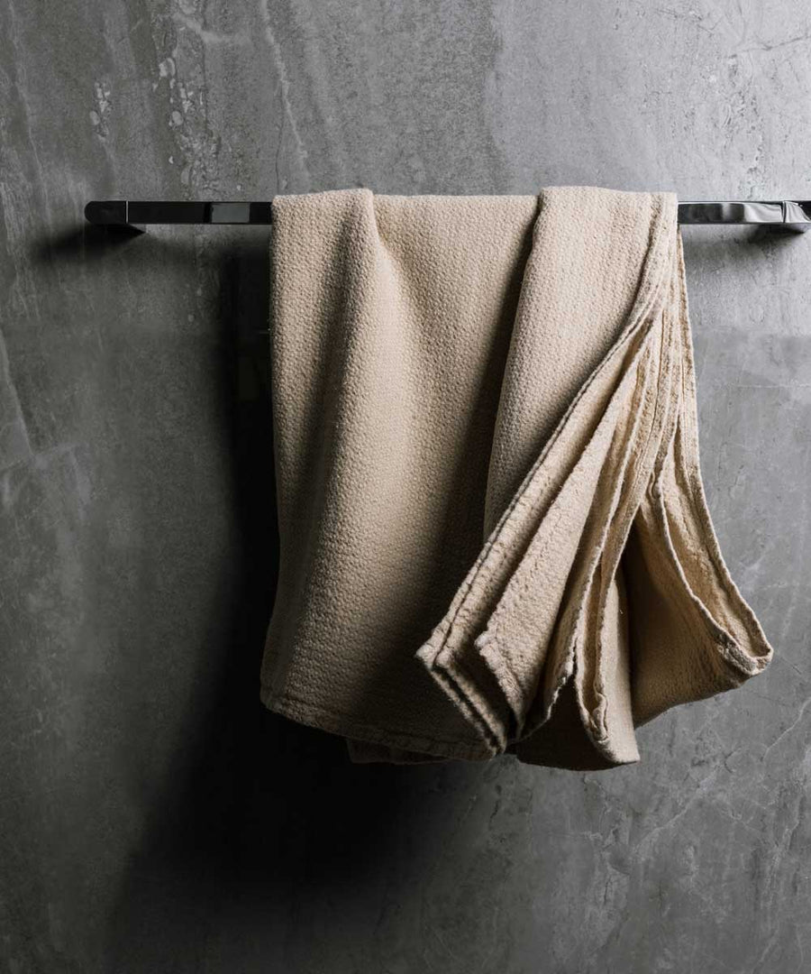 hanging photo of pure linen jacquard bath towel in natural colour with dark grey marble wall