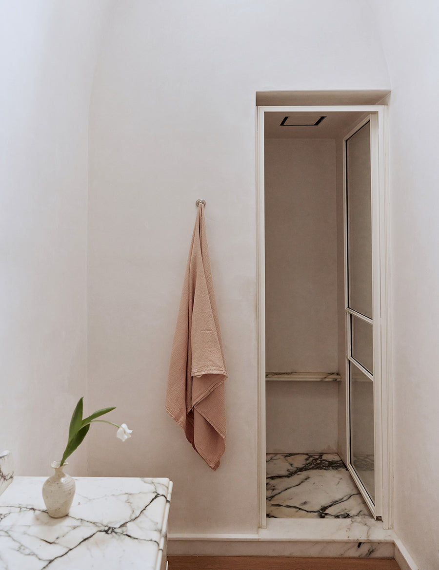 styled hanging pure linen jacquard bath towel in nude colour in a modern marble bathroom