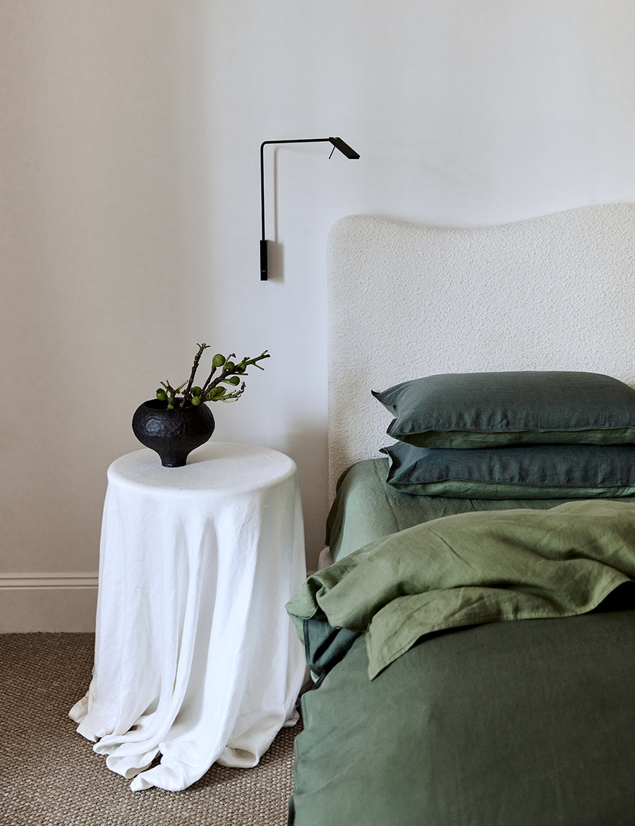 lifestyle shot of the linen reversible quilt set in cactus and celtic with modern decor and boucle headboard