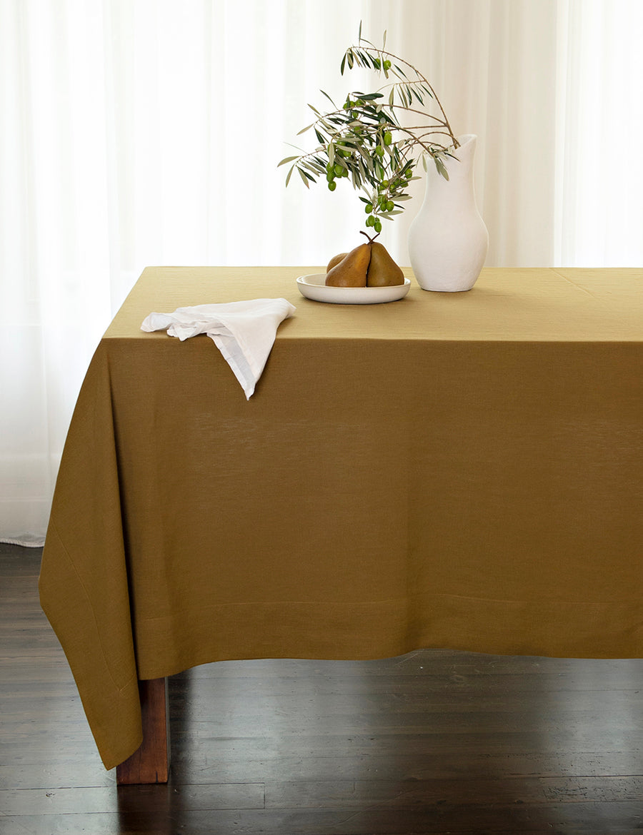 linen tablecloth in olive with pear and white vase